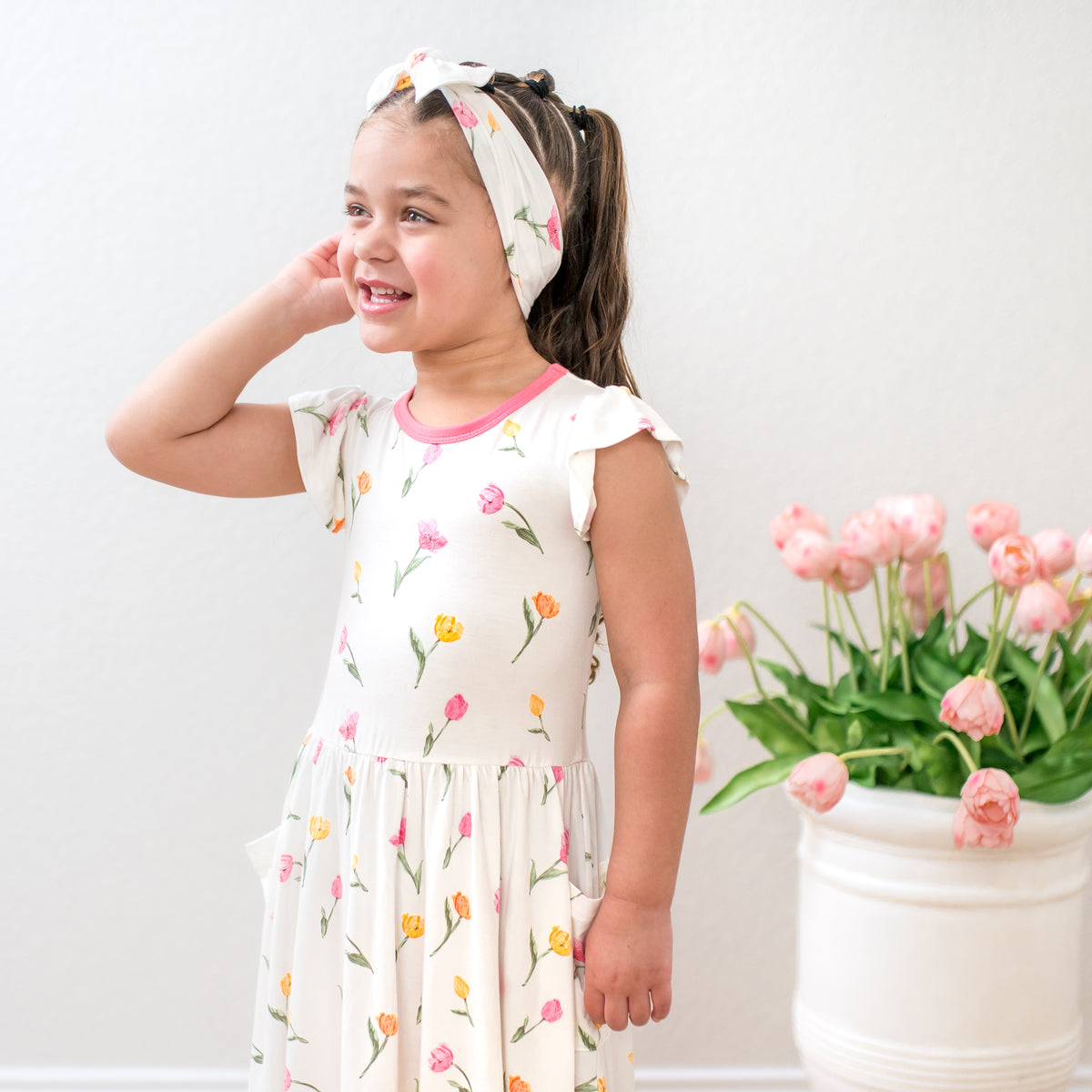 Young smile girl wearing the Pocket Dress in Tulip with matching headband 