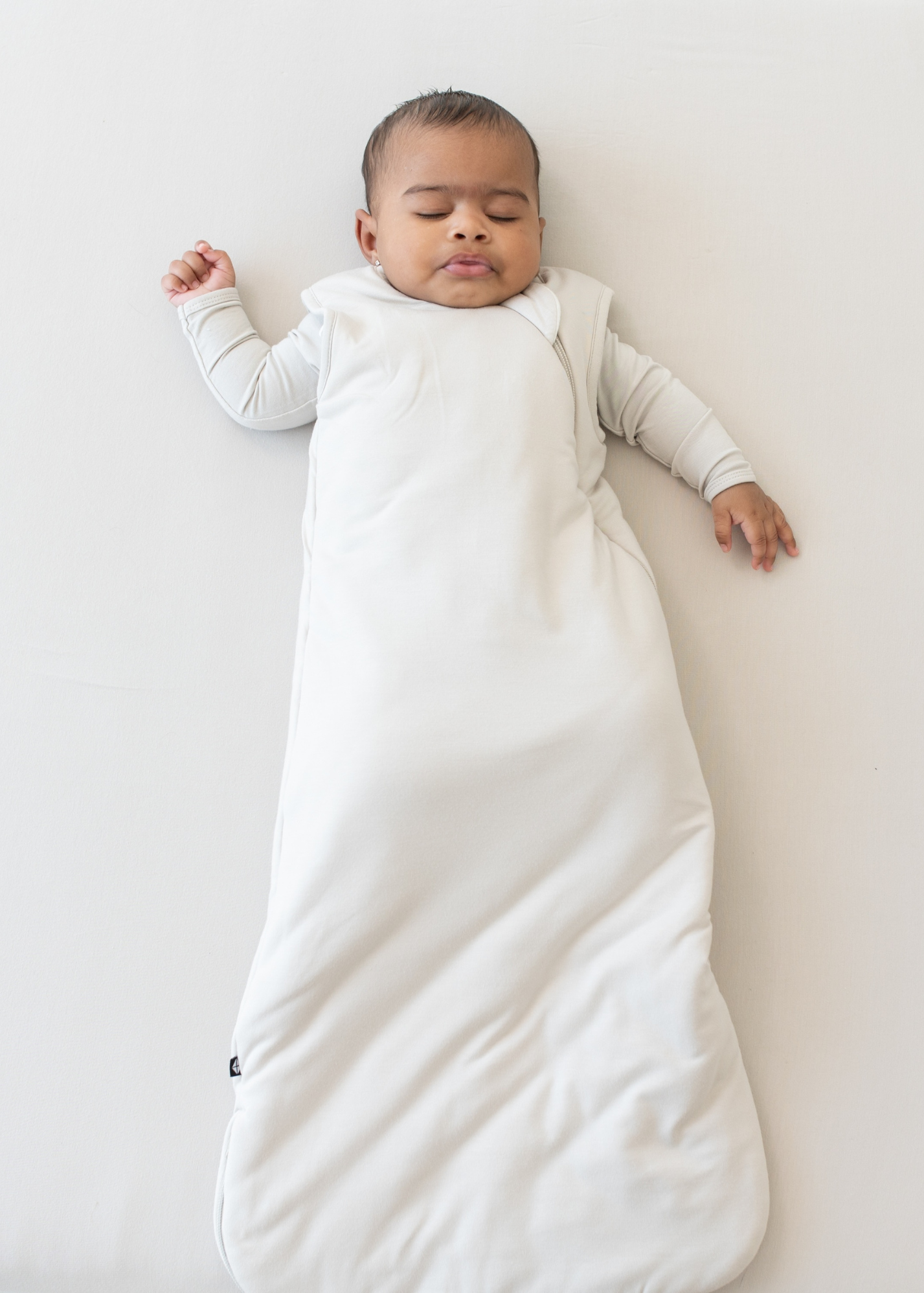 Baby lying in an off-white colored bamboo sleep sack