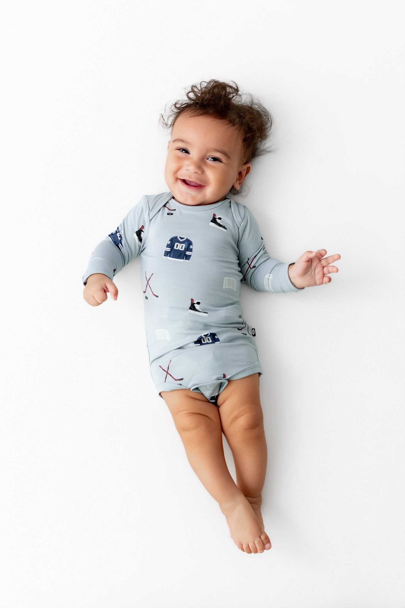 Baby wearing Long Sleeve Bodysuit in Vintage Hockey print on a white background