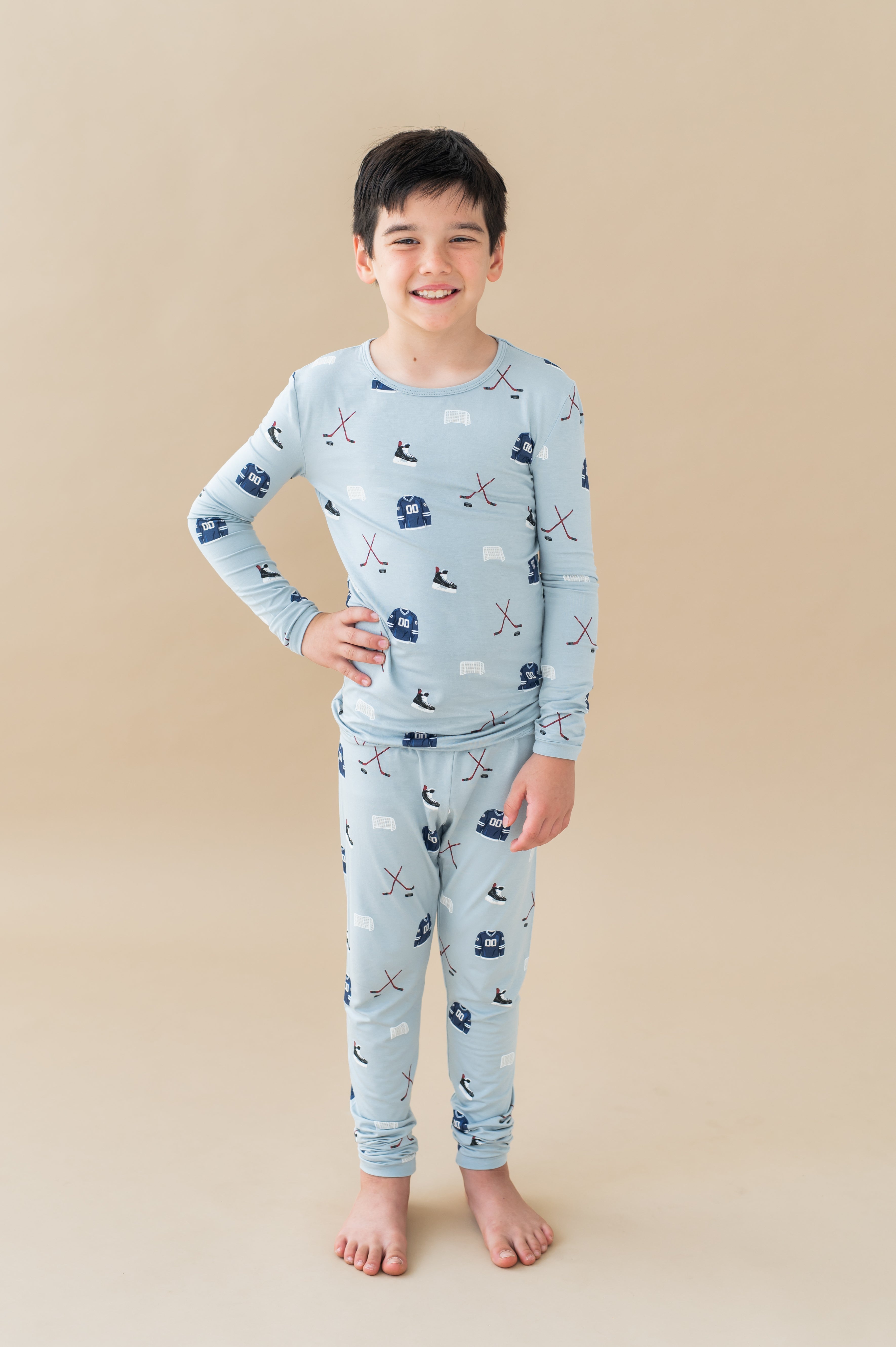 Boy wearing Long Sleeve Pajamas in Vintage Hockey print on a beige background