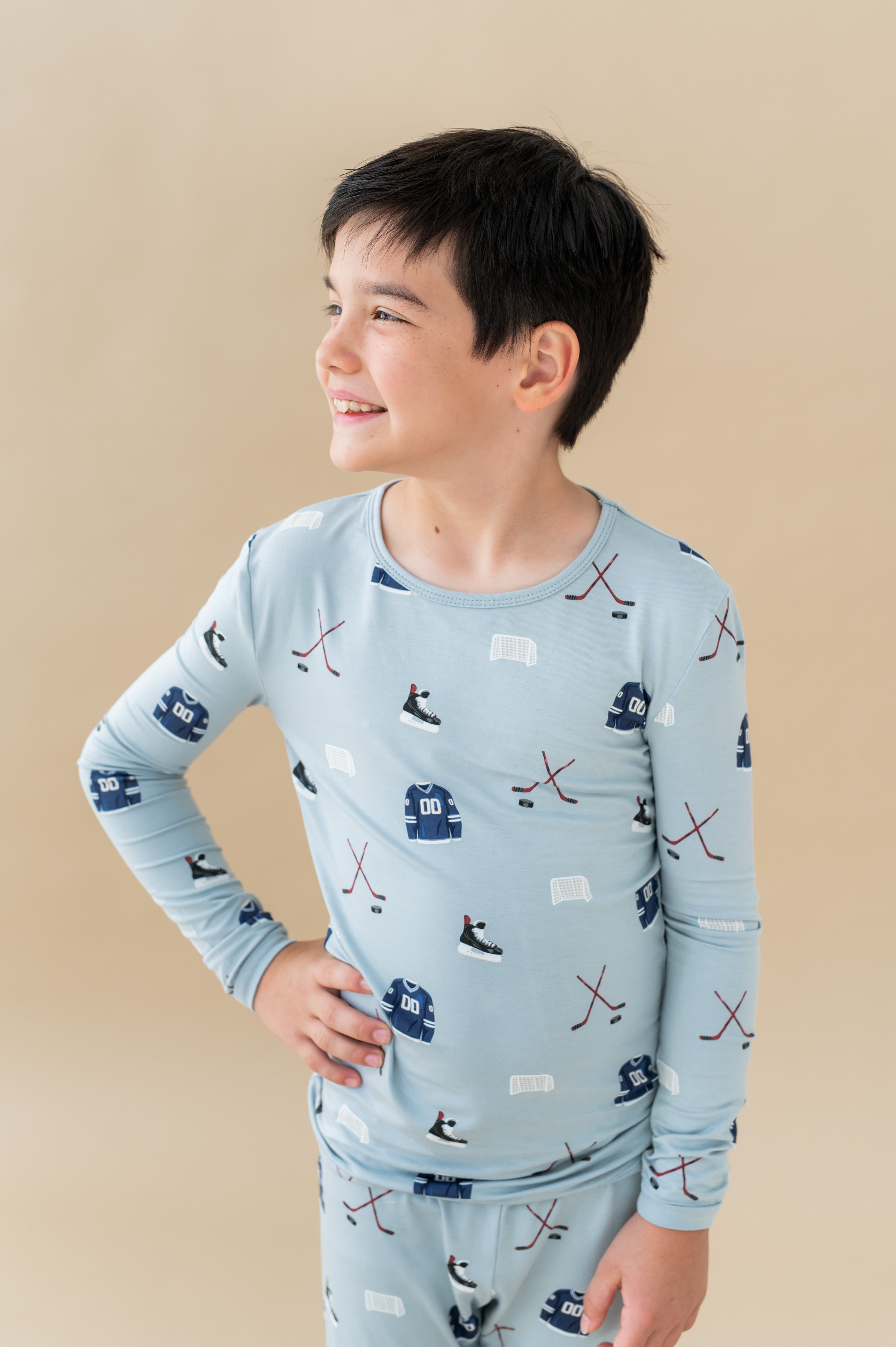 Close up of Boy wearing Long Sleeve Pajamas in Vintage Hockey print on a beige background