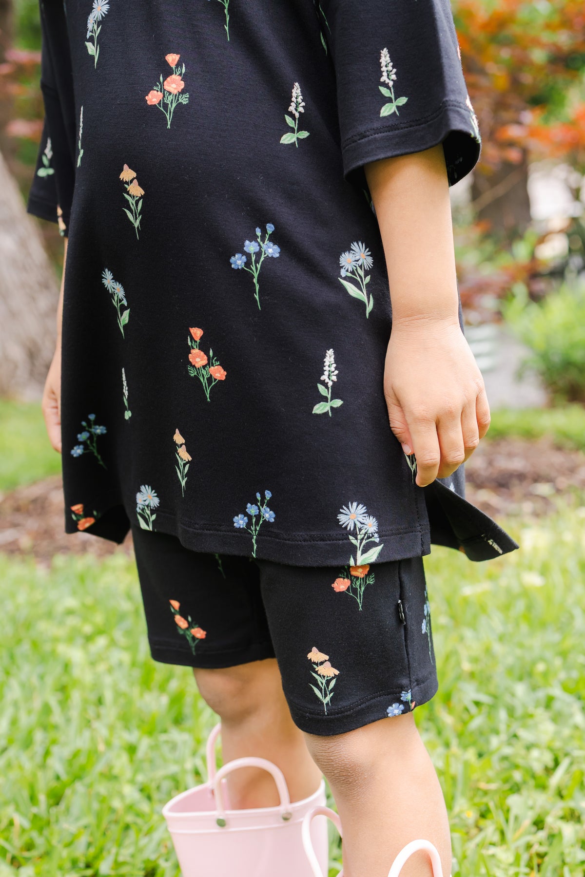 Girl standing outdoors in grass wearing Toddler Biker Short Set in Midnight Wildflower print 