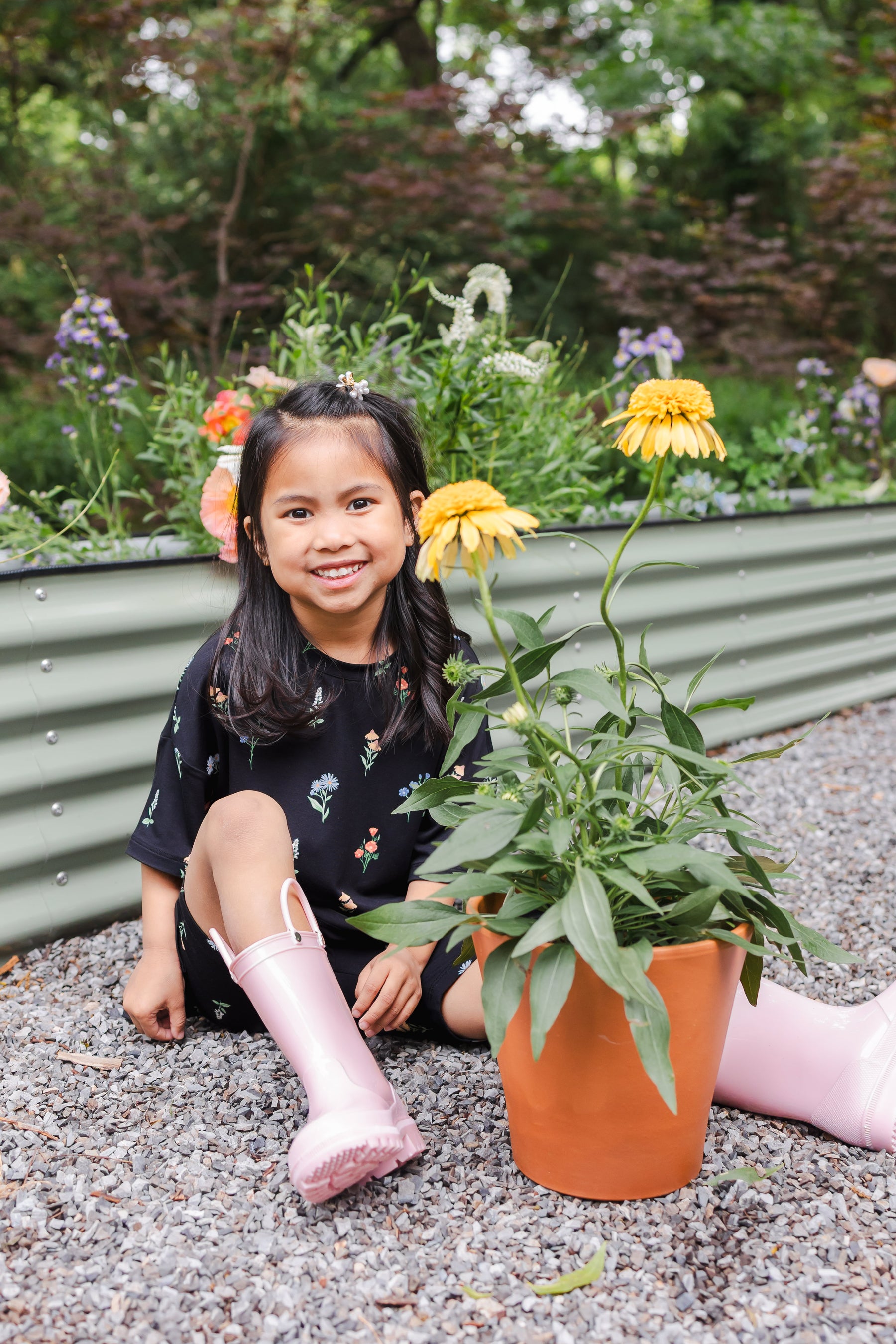 Girl sitting outdoors with flower pot wearing Toddler Biker Short Set in Midnight Wildflower print and pink boots