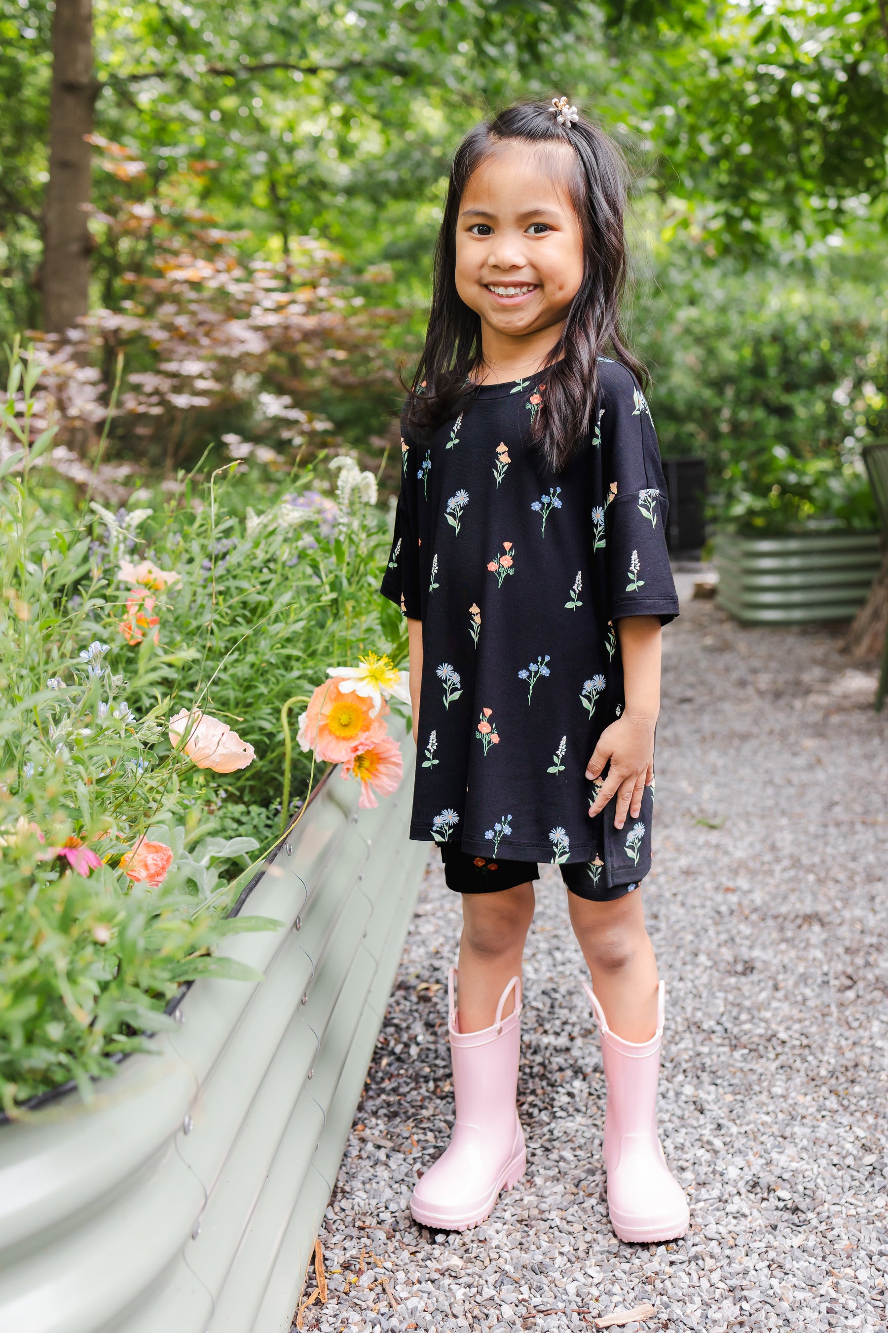 Girl standing outdoors wearing Toddler Biker Short Set in Midnight Wildflower print and pink boots