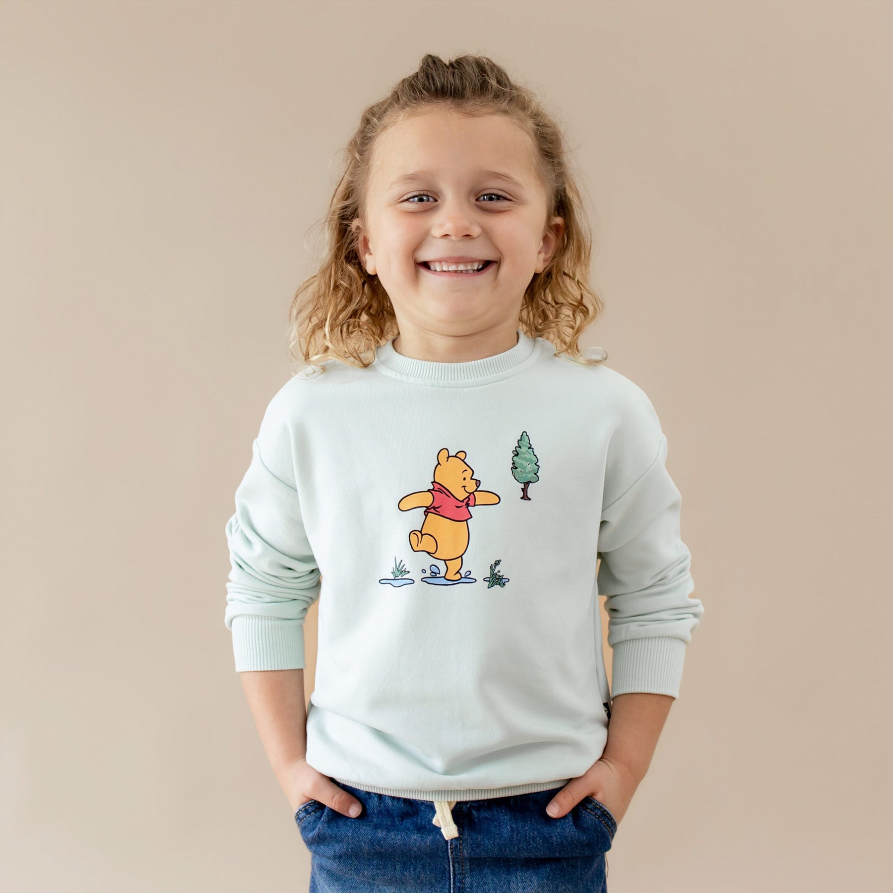 Smiling child wearing the Sweatshirt in Winnie the Pooh on Dew with their hands in he pockets of their jeans