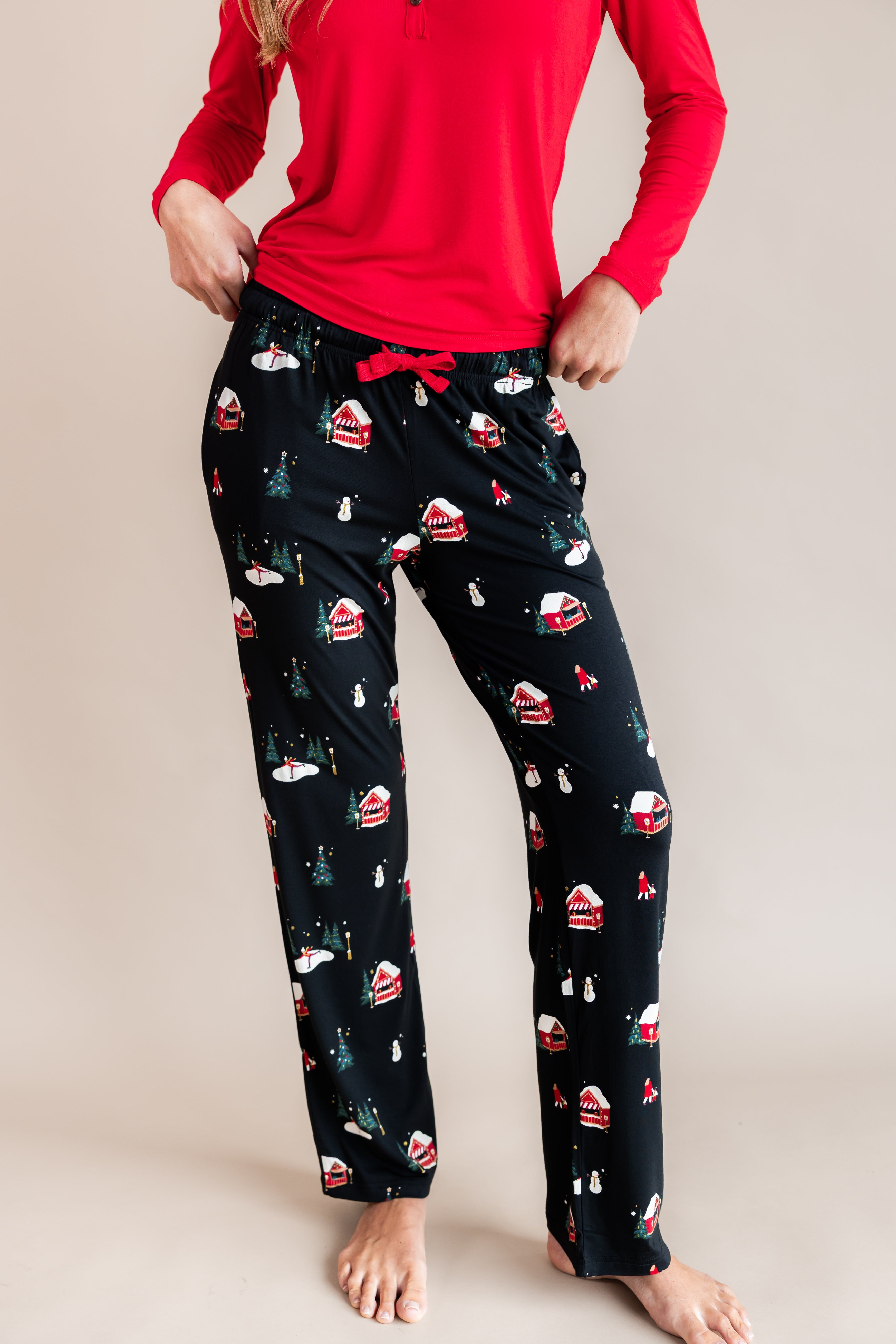 Modal wearing women's lounge pants in winter wonderland print over red T-shirt on a beige background