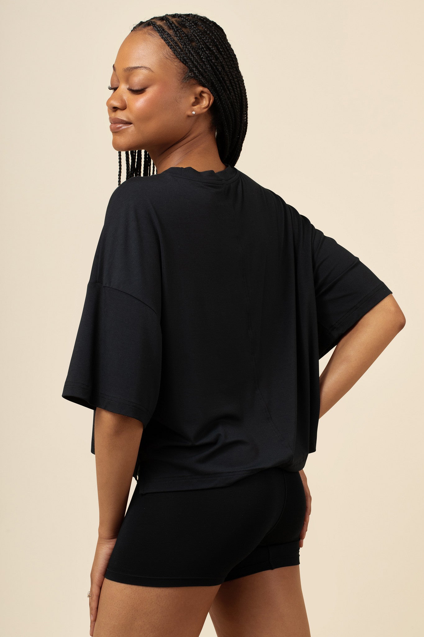 Woman wearing a black outfit against a beige background