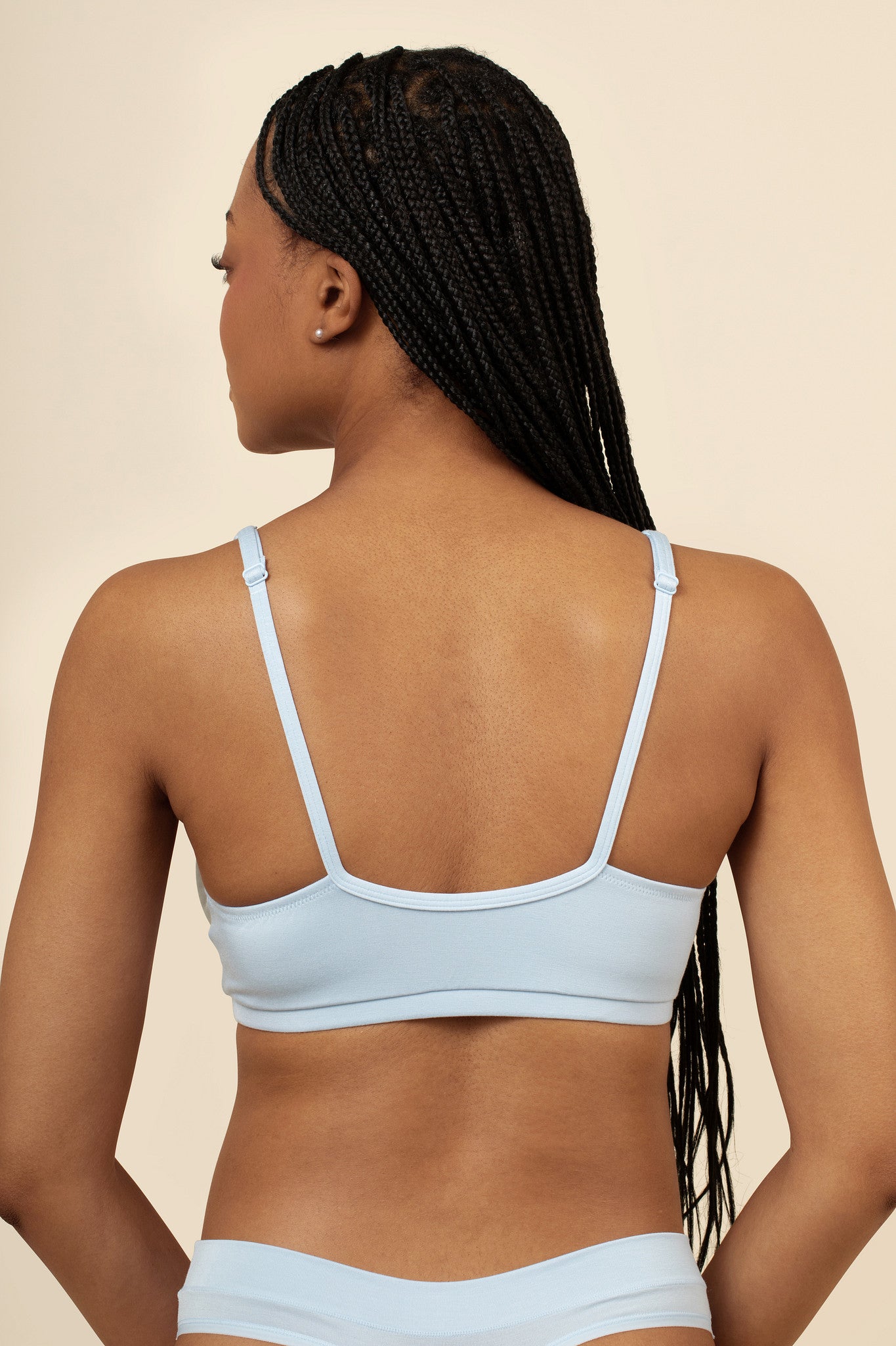 Woman wearing a light blue bra set on a beige background