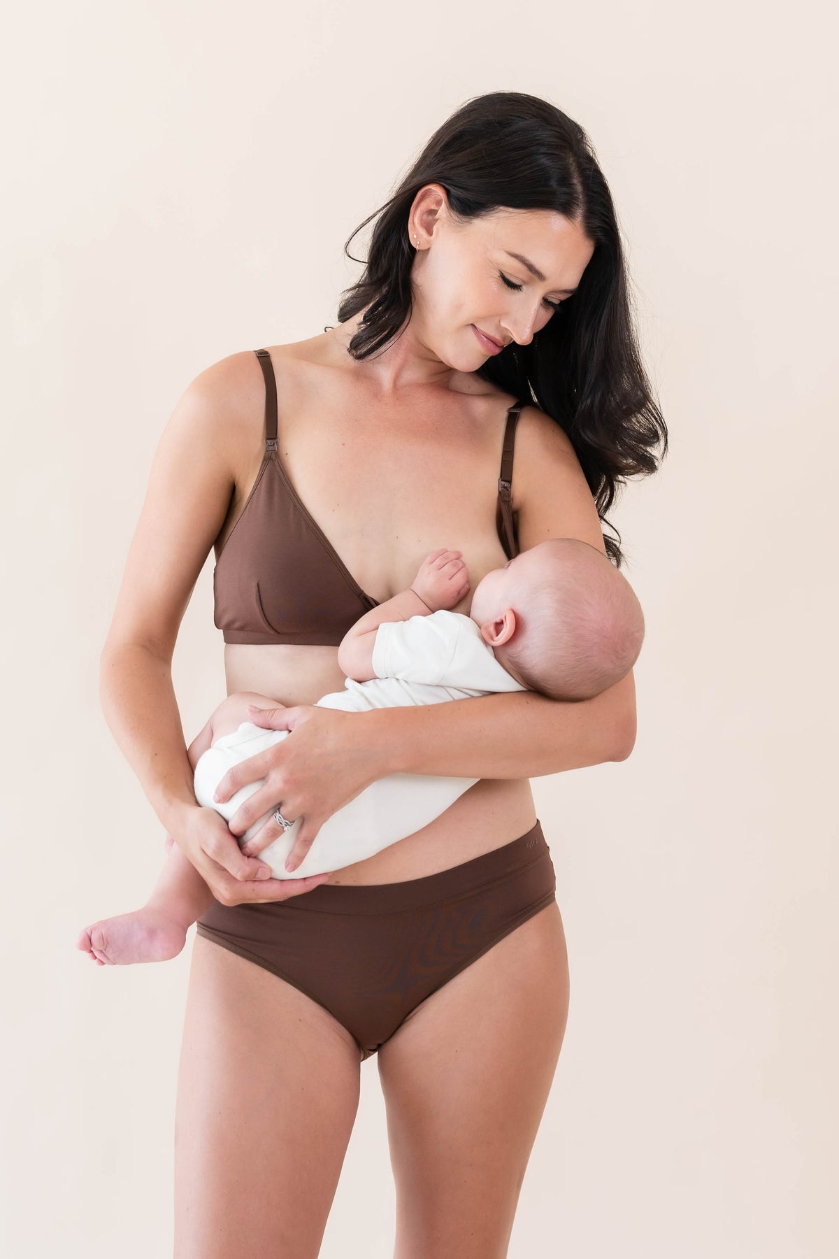 Female model nursing her infant wearing the Women's Nursing Bra in Latte