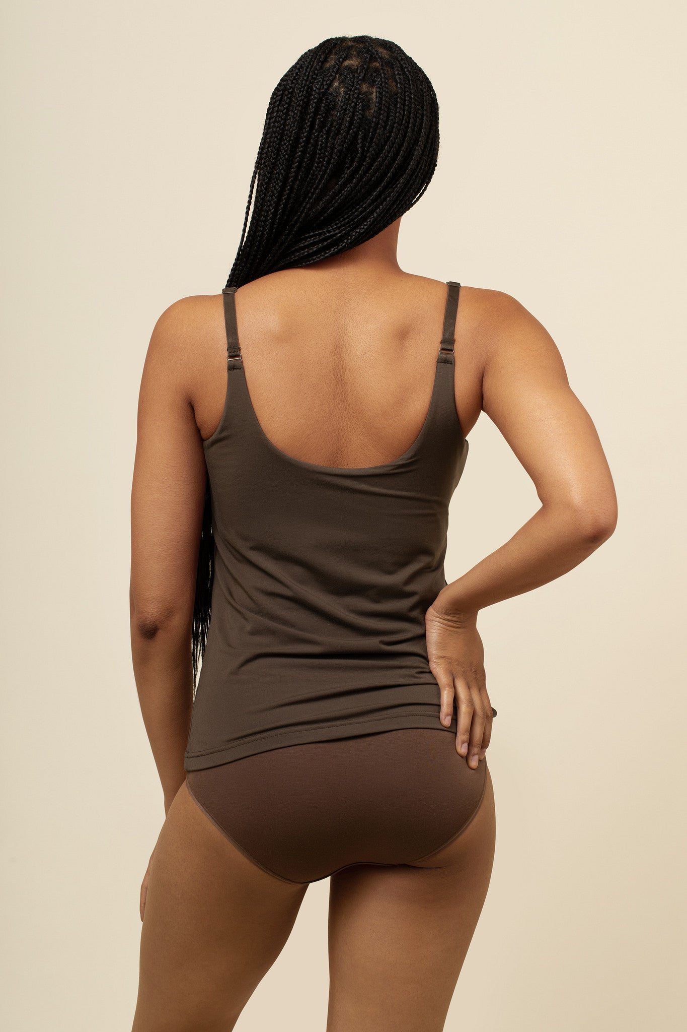 Person wearing a brown tank top and underwear set on a beige background