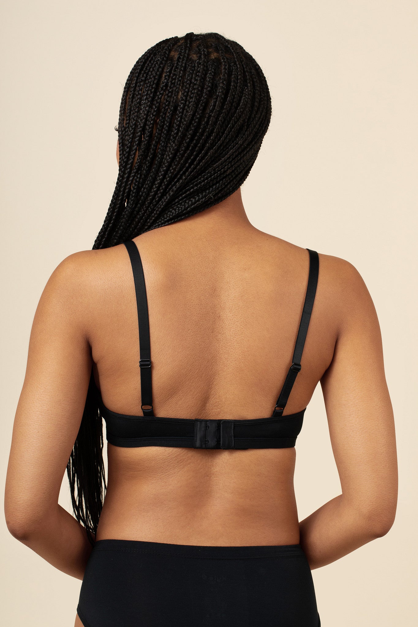 Person wearing a black bralette on a beige background