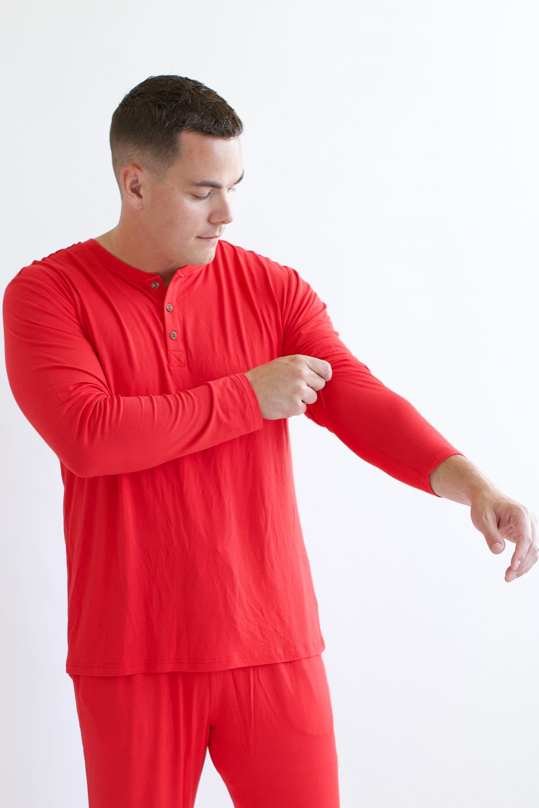 Male model pulling the sleeve up on the Men's Long Sleeve Henley Top in Cardinal
