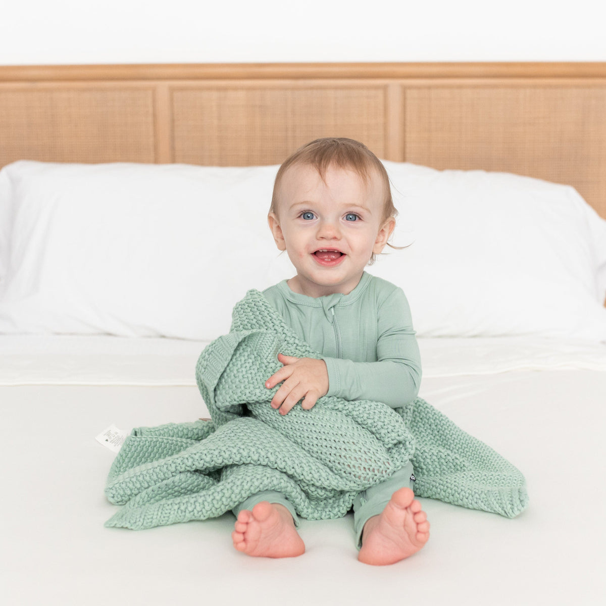 Infant wrapped in Kyte Baby Chunky Knit Baby Blanket in Sage Green