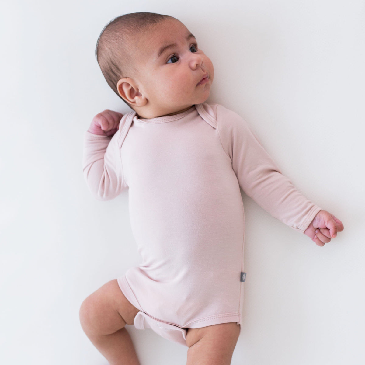 Baby wearing Kyte Baby Long Sleeve Bodysuit in Blush