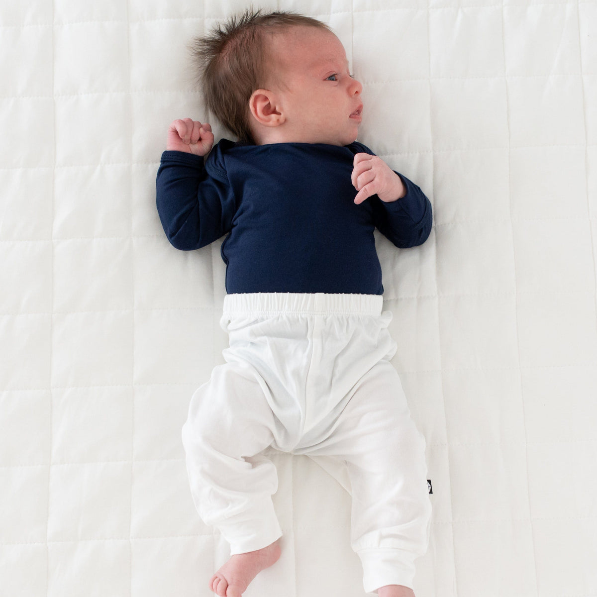 Newborn laying on white background wearing Kyte Baby  Pant in Cloud white