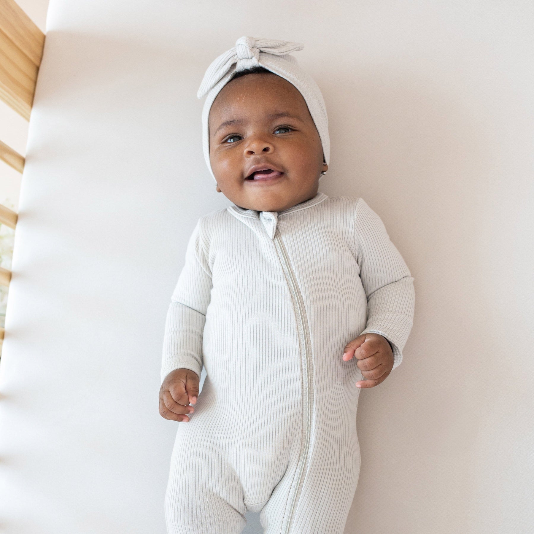 Infant wearing Kyte Baby Ribbed turban style Headwrap in Oat