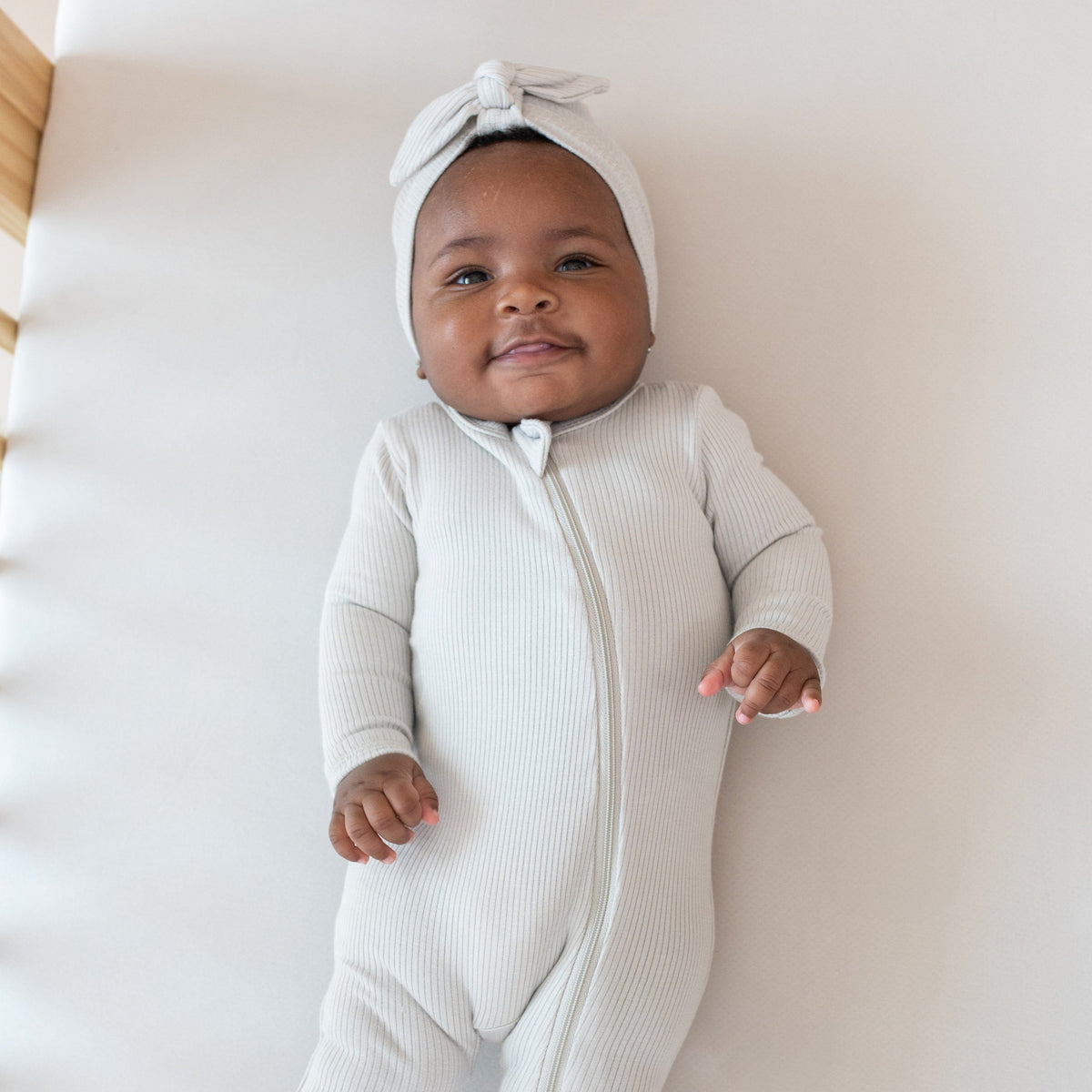 Baby wearing Kyte Baby Ribbed Zippered Footie in Oat