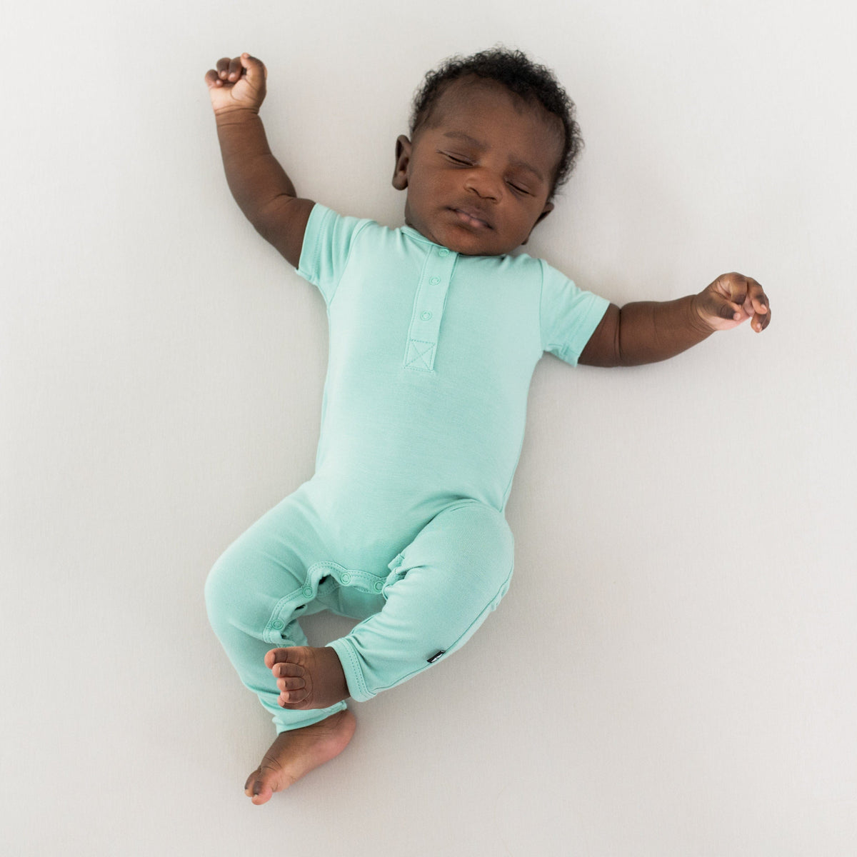 Baby wearing Kyte Baby Short Sleeve Snap Romper in Wasabi