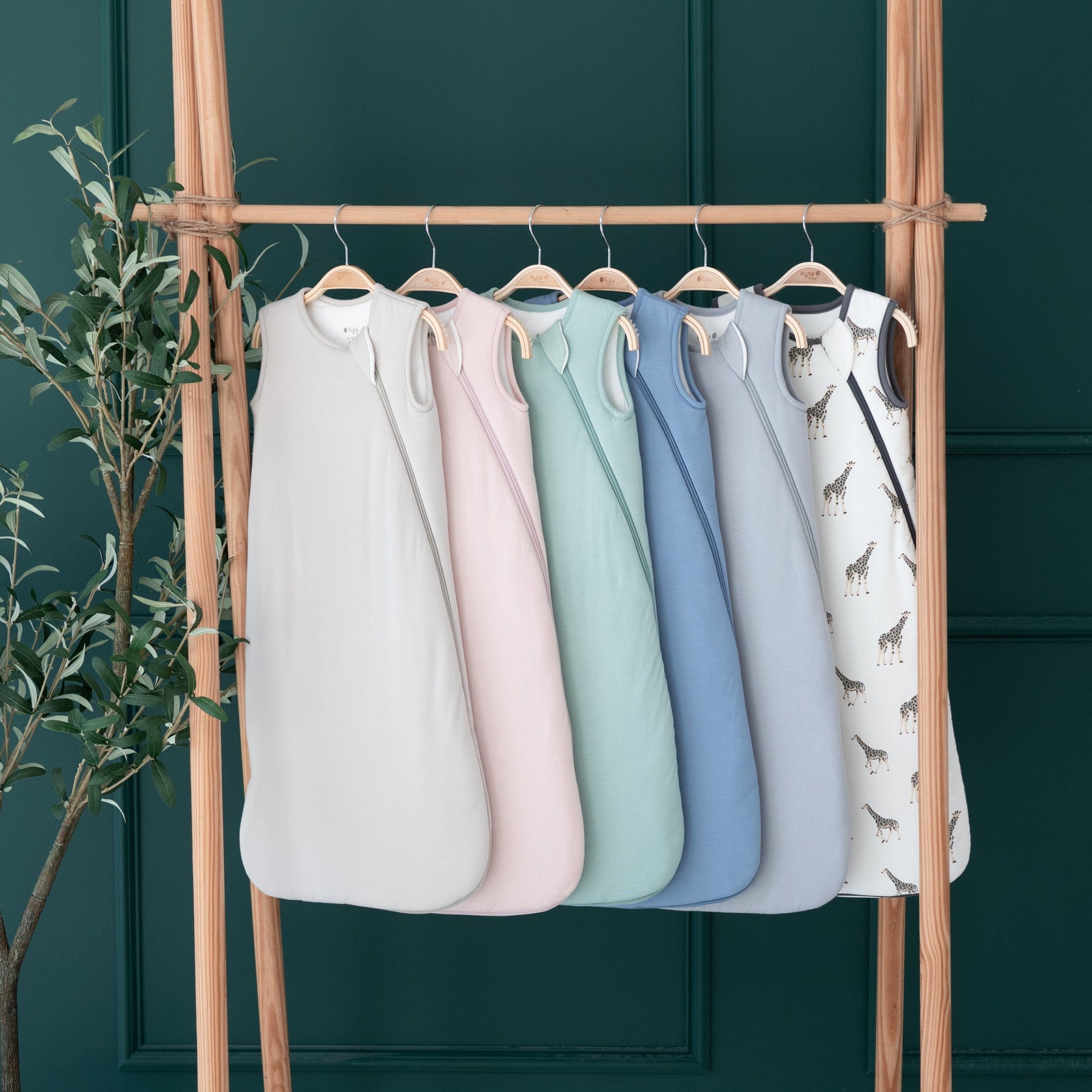 Different colors of Kyte Baby 2.5 TOG Sleep Bags hanging on wooden rack