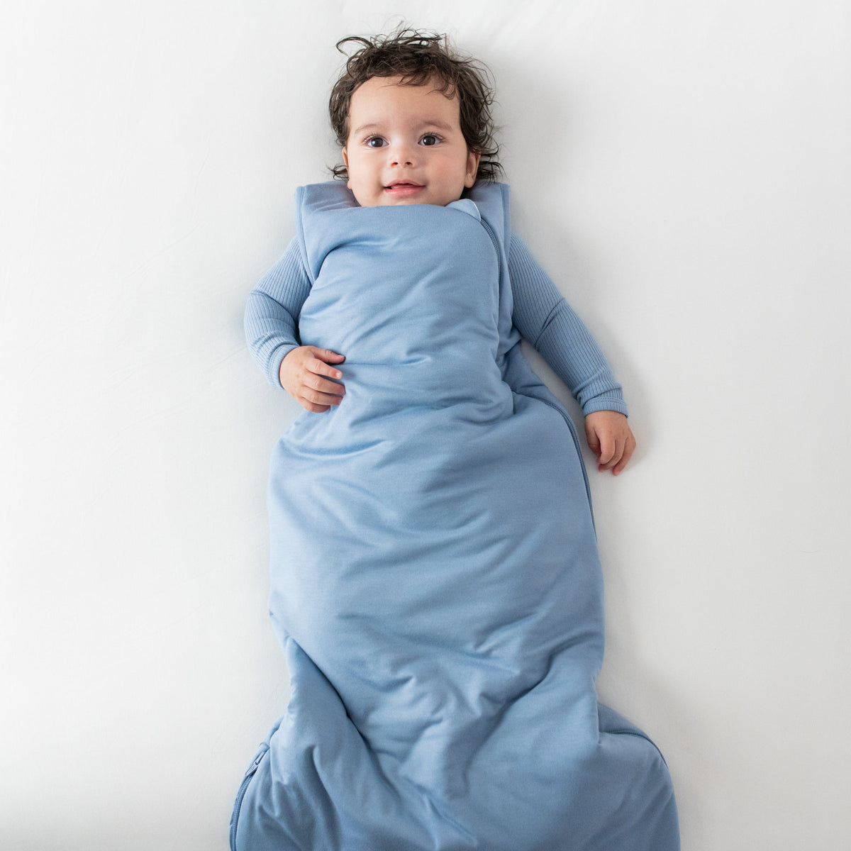 Baby wearing Kyte Baby Sleep Bag in Slate 2.5 with Ribbed Slate Bodysuit underneath 