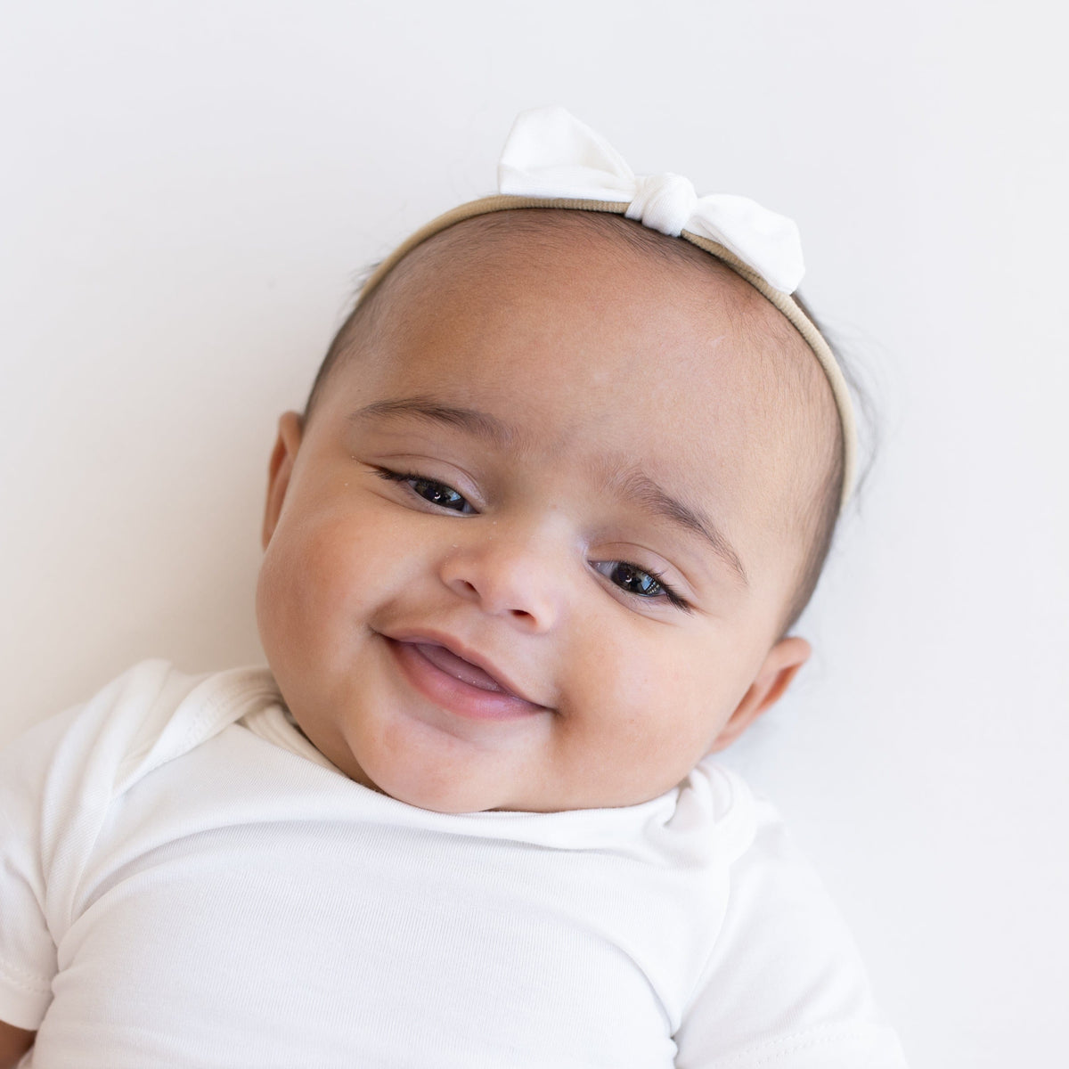 Smiling Infant wearing a Tiny Nylon Bow in Cloud 