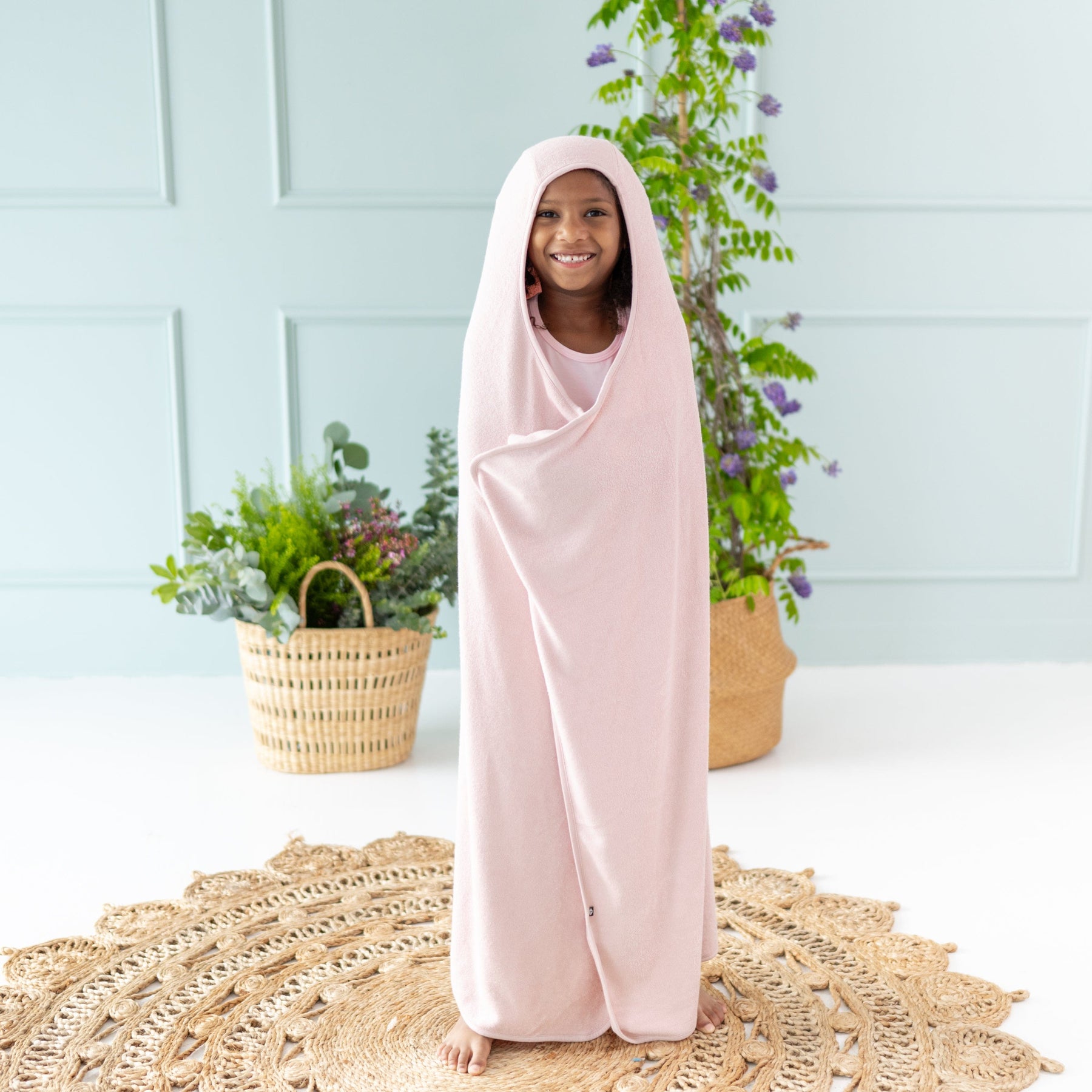 Child wrapped in Kyte Baby Toddler Hooded Bath Towel in Blush pink