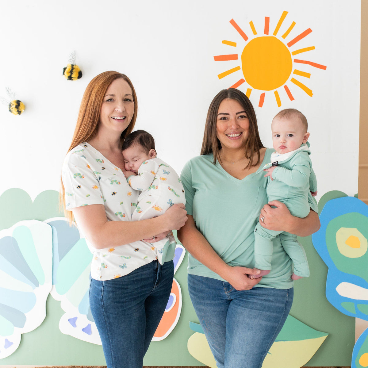Women holding their infants in matching Kyte Baby outfits