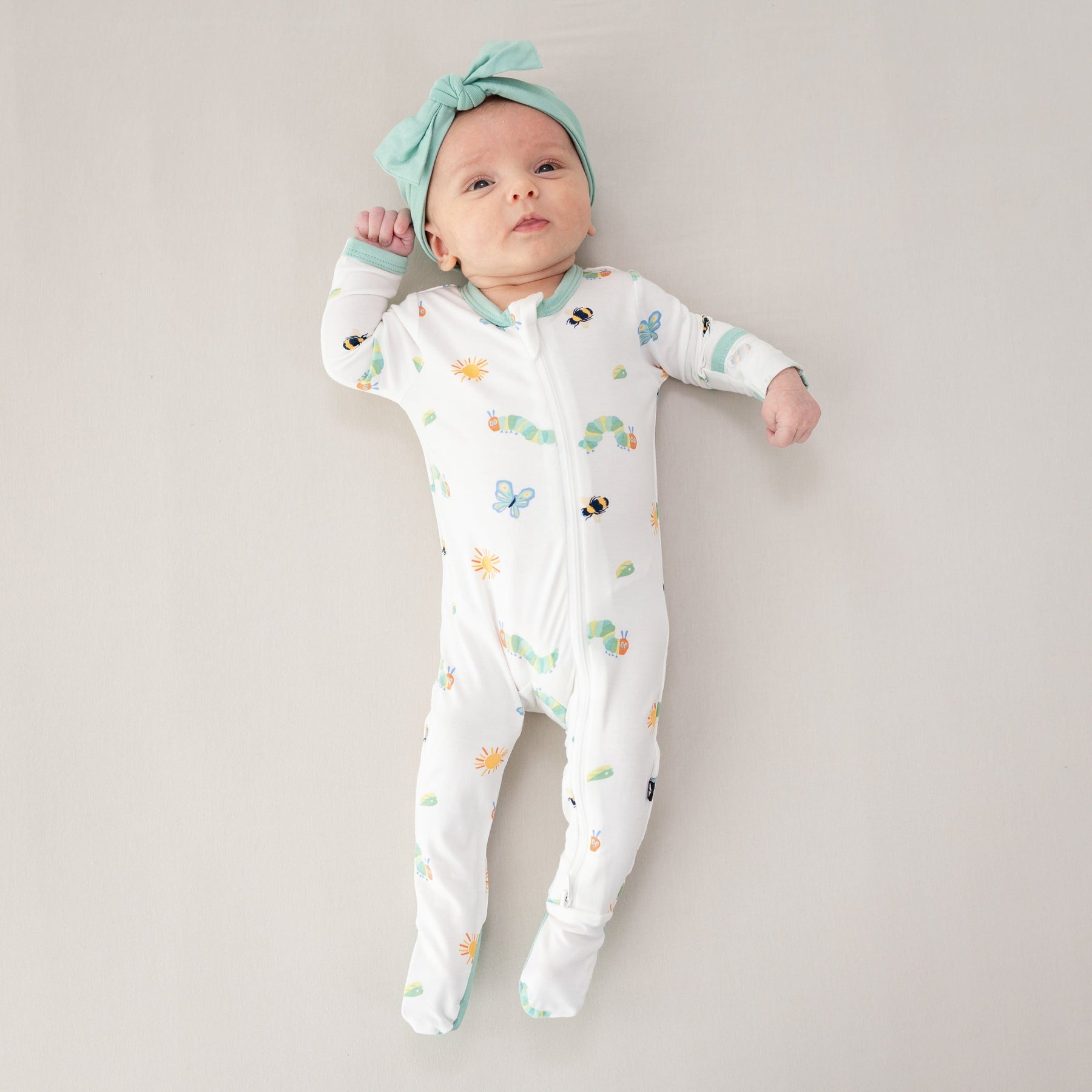 Infant model wearing the Zippered Footie in The Very Hungry Caterpillar™ and Friends with Wasabi Knotted Bow