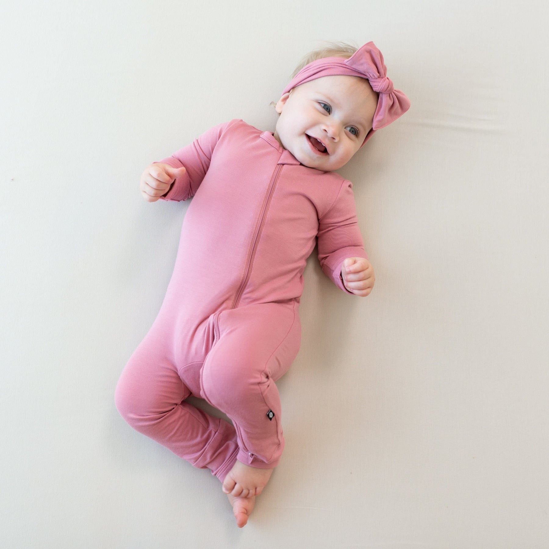 Infant wearing Zippered Romper in Apple Blossom with matching bow headband
