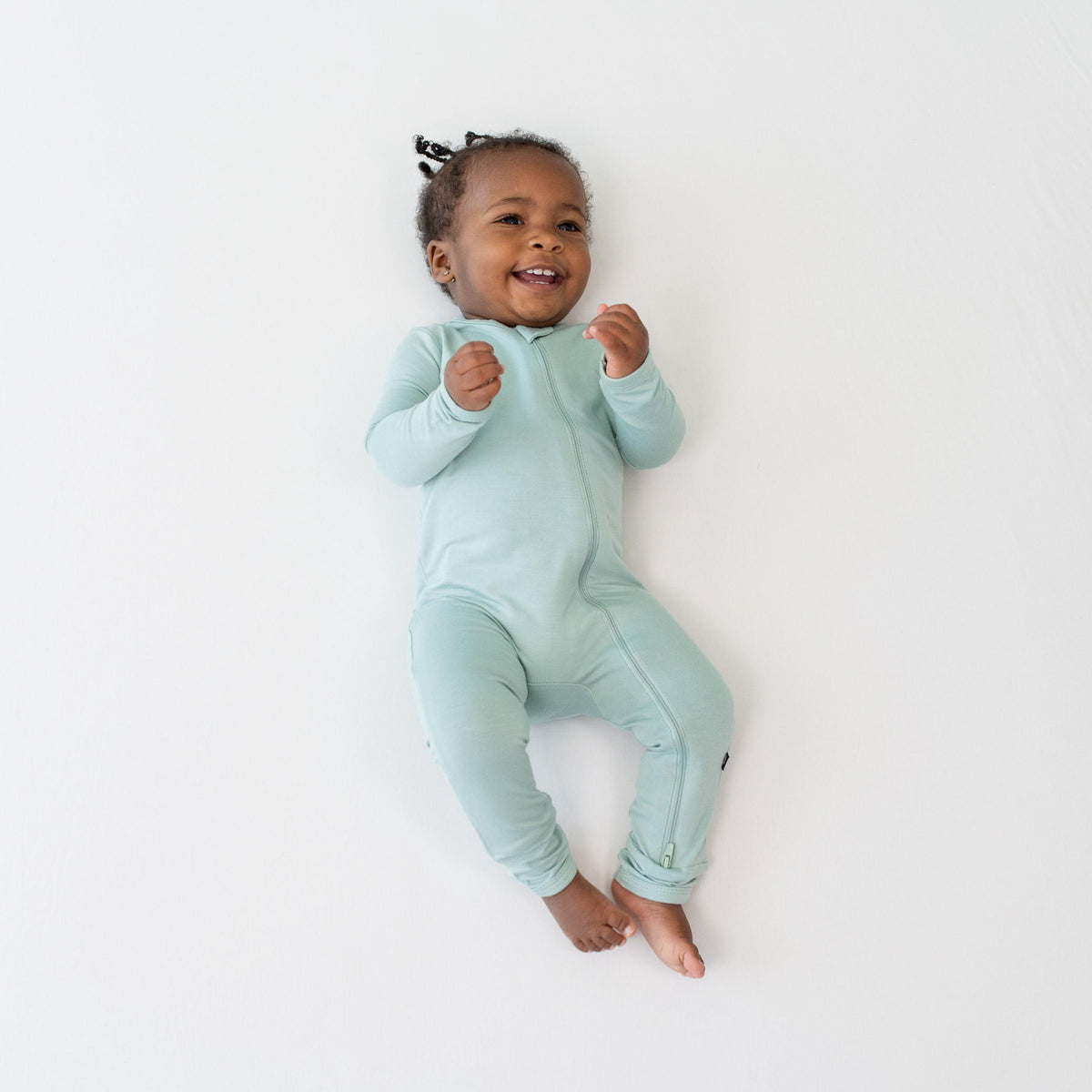 Infant model wearing a  Kyte Baby Zippered Romper in Sage