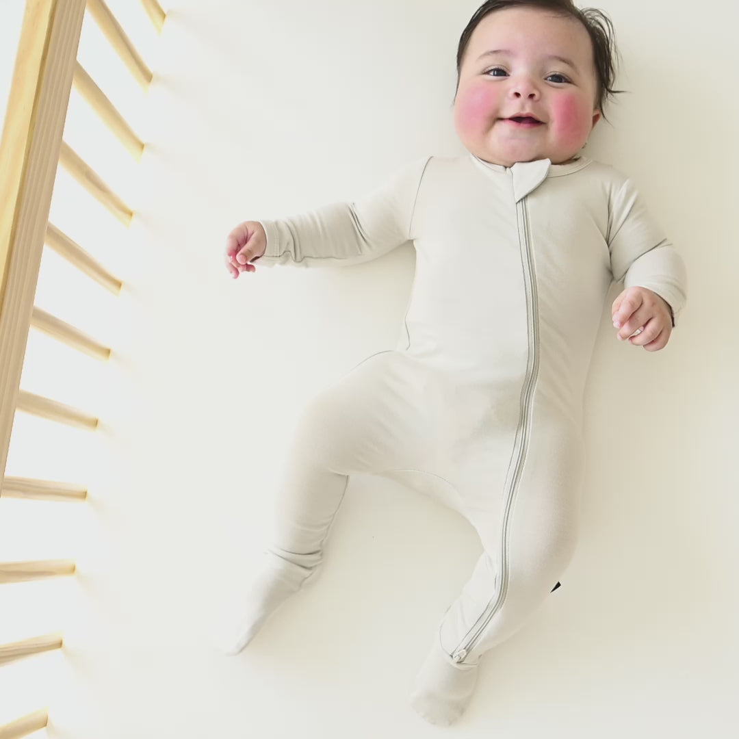 Video of infant laying in a crib wearing the Zippered Footie in Oat