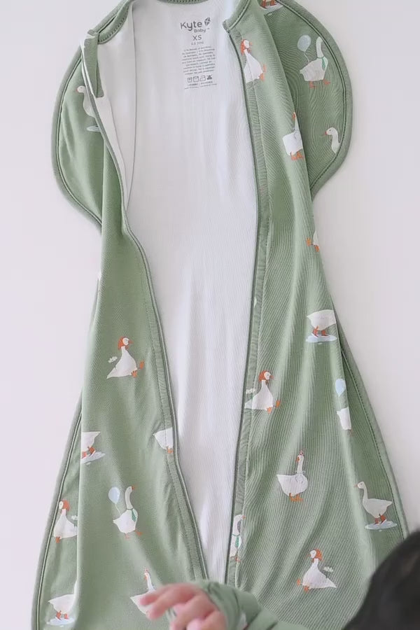 Video of a baby being swaddled in a green swaddle bag with silly goose pattern