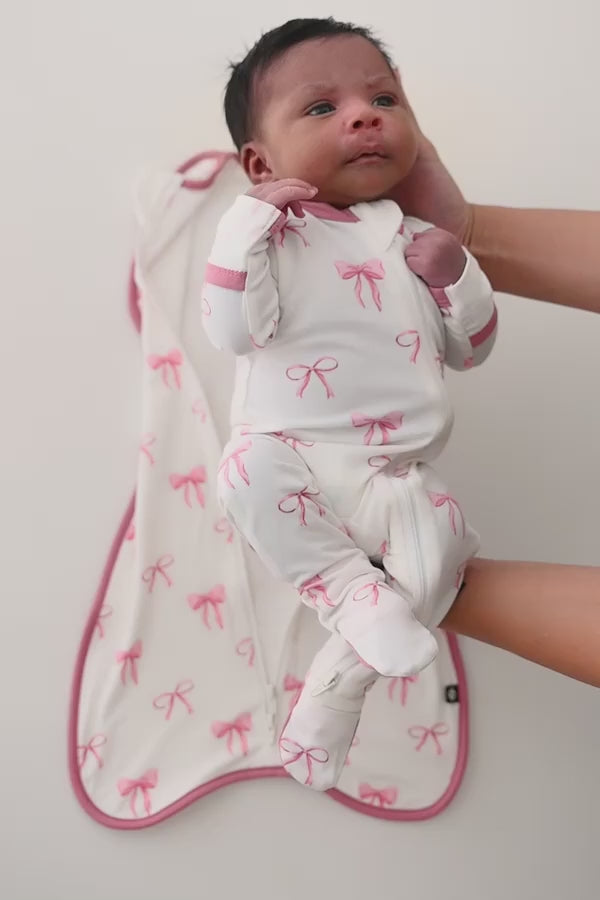 Video of baby being swaddled in a bow patterned swaddle bag
