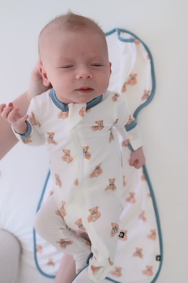 Video of baby being swaddled in a teddy bear patterned swaddle bag