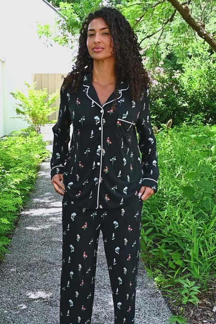 Woman modeling a black long sleeve pajama set with wildflower pattern in an outdoor setting