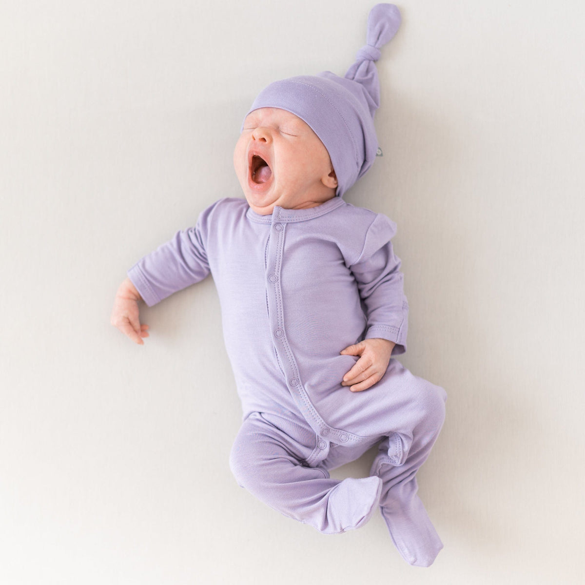 Yawning newborn wearing Knotted Cap in Taro with matching Snap Footie