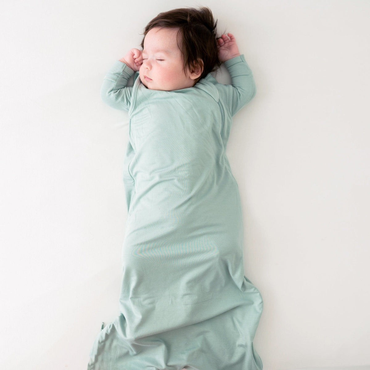 Sleeping baby wearing the Kyte Baby Sleep Bag in Sage TOG 0.5