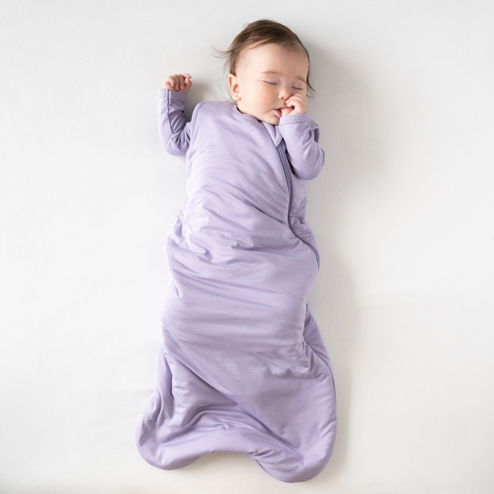 Sleeping baby sucking her thumb in Kyte Baby Sleep Bag in Taro 1.0 TOG