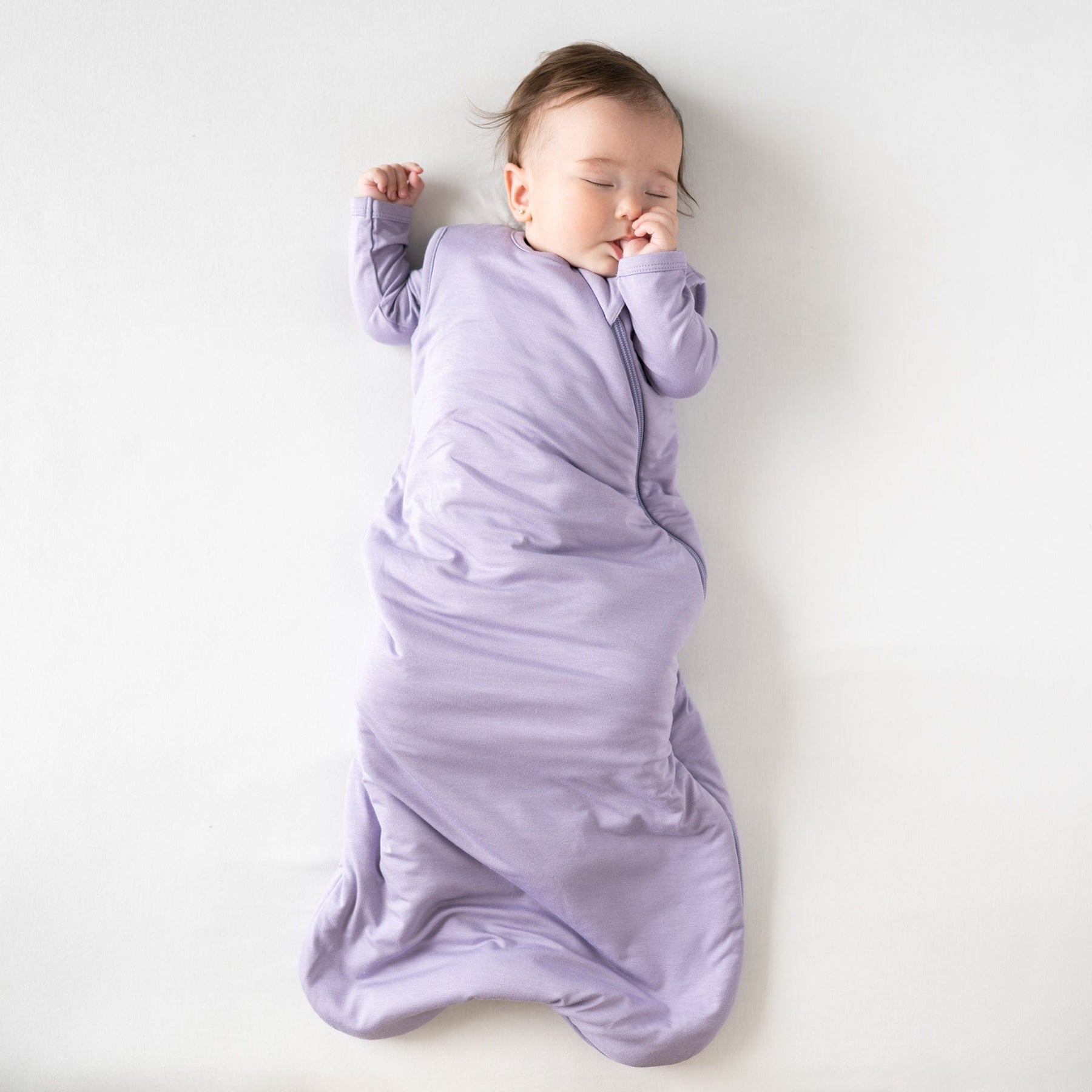 Sleeping baby sucking her thumb in Kyte Baby Sleep Bag in Taro 1.0 TOG