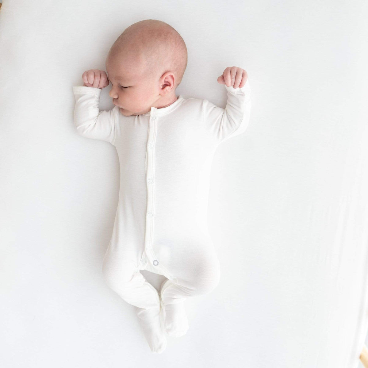 Sleeping infant wearing  Kyte Baby Snap Footie in Cloud