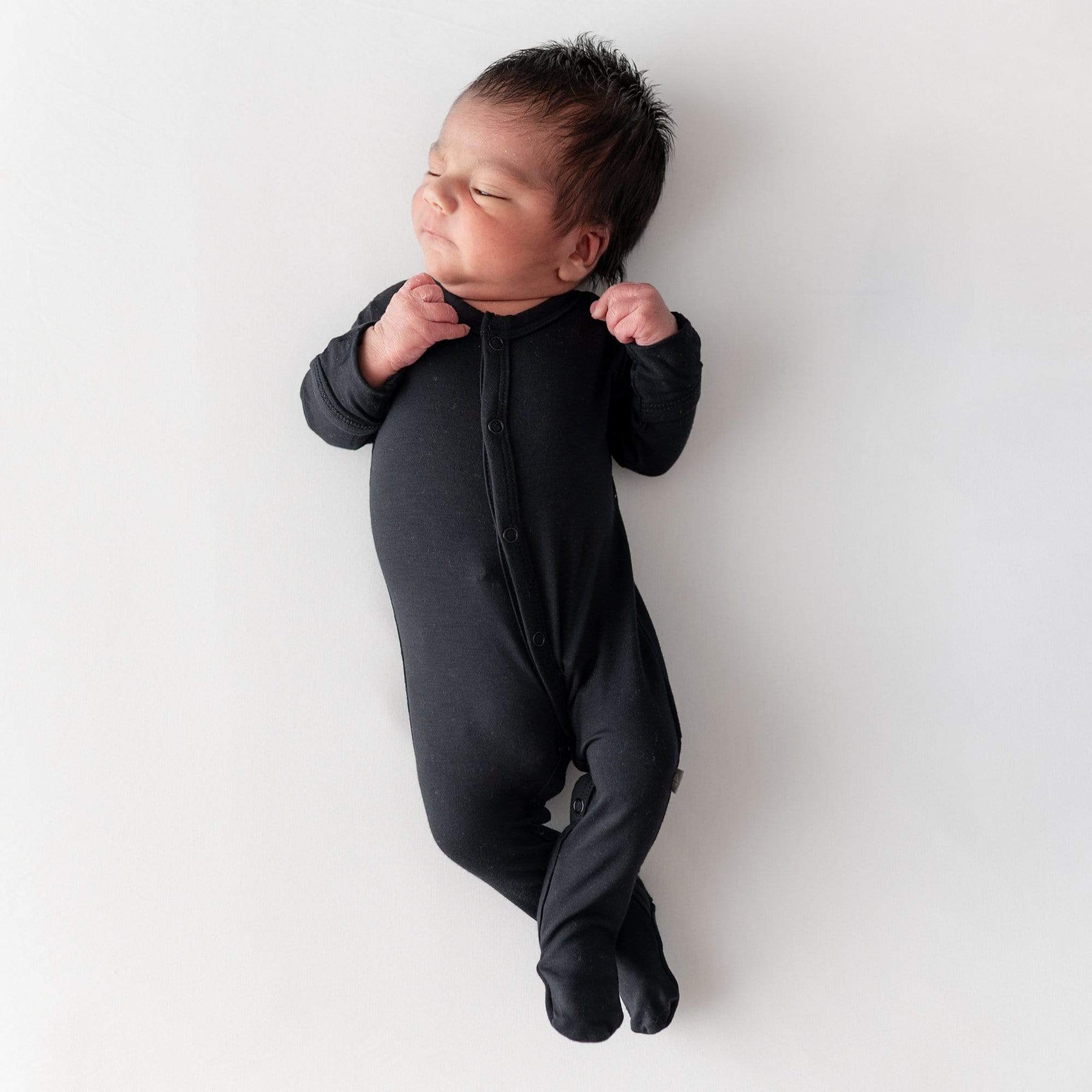 Sleeping newborn wearing Kyte Baby Footie in Midnight